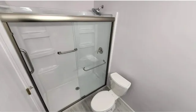 a white toilet sitting next to a shower