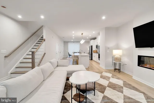 a living room with furniture a flat screen tv and kitchen view