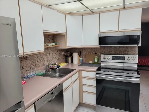 a kitchen with stainless steel appliances granite countertop a refrigerator a sink a stove a microwave and wooden cabinets