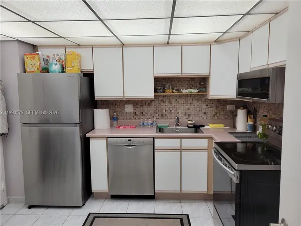 a kitchen with a refrigerator sink and cabinets