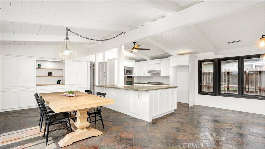 3317 Lees Avenue Long Beach, CA 90808 - Photo 10 of 75 View across the natural slate floors over the large dining area into the roomy island-style kitchen with new cabinet doors, skylight for even more natural light and an enviable wall of pantry storage with butcher block prep area.