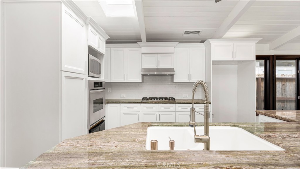 3317 Lees Avenue Long Beach, CA 90808 - Photo 13 of 75 Natural earthy toned granite counters with island sink opens to the new kitchen cabinet doors, new gas cooktop and new exhaust vent hood.