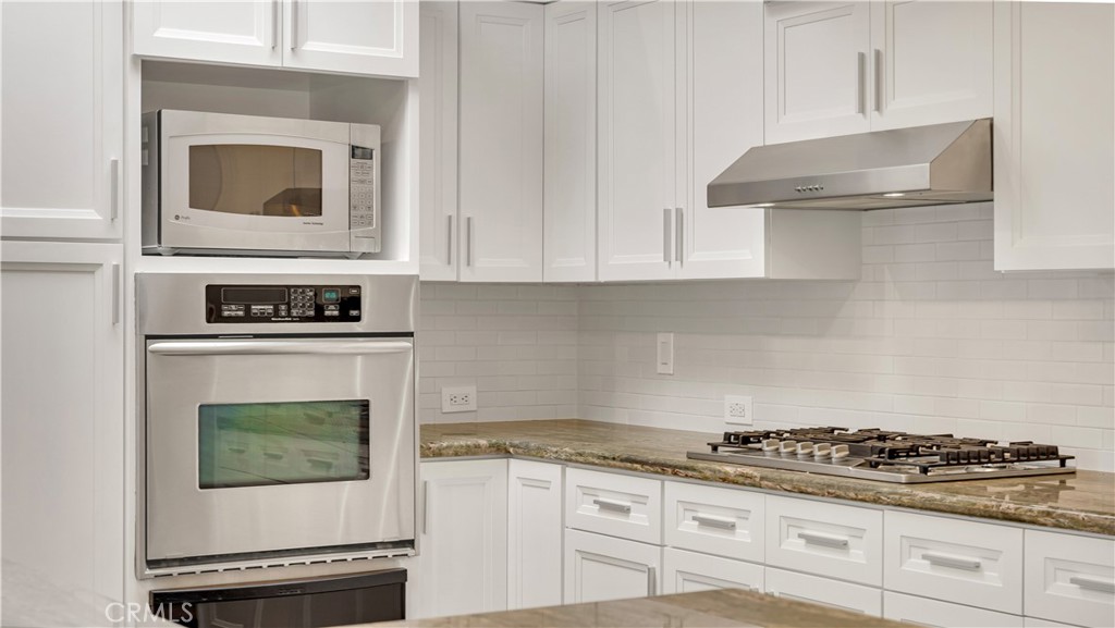 3317 Lees Avenue Long Beach, CA 90808 - Photo 17 of 75 White Subway tile backsplash keeps the kitchen clean, simple and just right to showcase the slate floors, earthy tones stone counters, sleek new cabinet door designs and space that is filled with natural light.