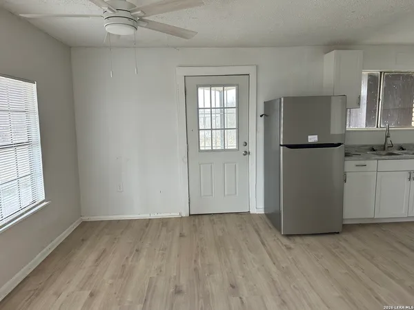 an empty room with wooden floor cabinet and windows