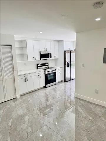 a large white kitchen with cabinets and stainless steel appliances