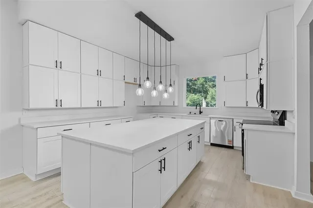 a kitchen with a sink dishwasher stove and white cabinets