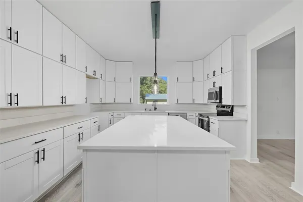 a view of an empty room with wooden floor and a bathroom