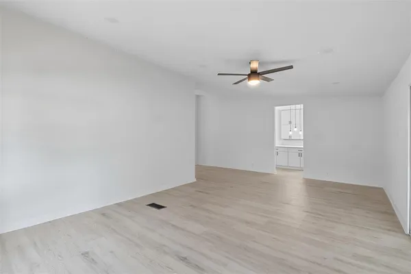 a view of an empty room with wooden floor and closet