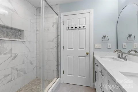 a bathroom with a double vanity sink a mirror and shower
