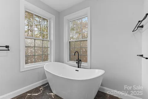 a white bath tub sitting in a bathroom next to a window