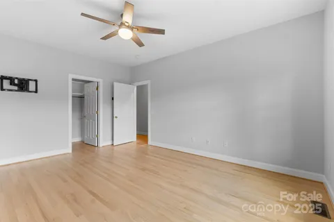 a view of an empty room with window and wooden floor