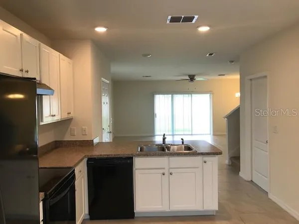 a kitchen with granite countertop white cabinets and black appliances