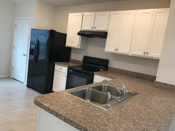 a kitchen with stainless steel appliances granite countertop a refrigerator a stove a sink and dishwasher