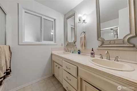a bathroom with double vanity sink and two mirror