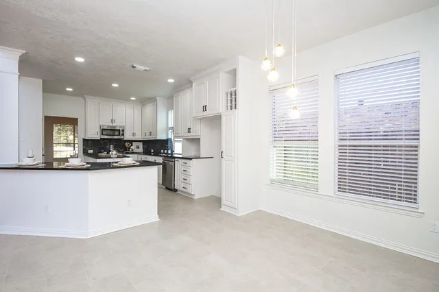 a kitchen with granite countertop a sink white cabinets and white appliances