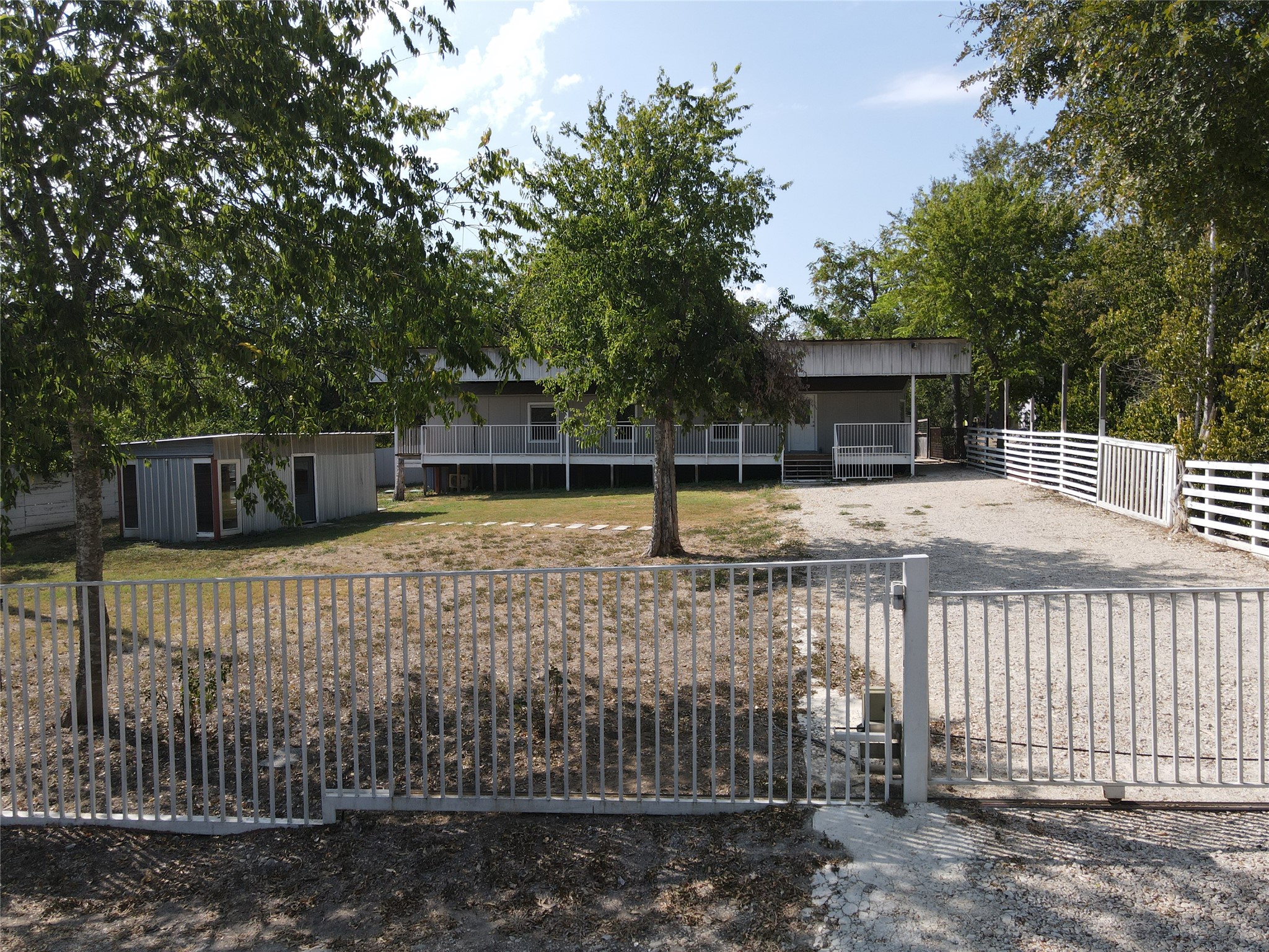 155 5th Street Maxwell, TX 78656 - Photo 1 of 1 View of front of house with gravel driveway, an outbuilding, and a gate