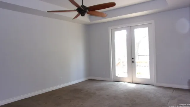 an empty room with windows and fan
