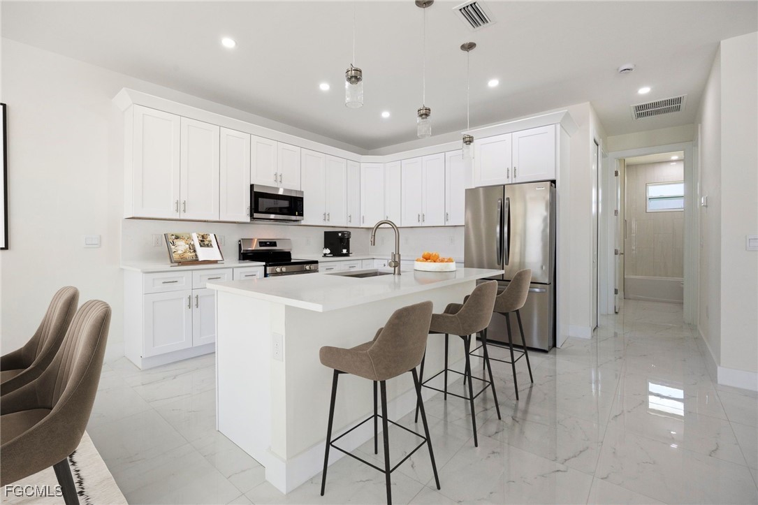 3002 Mercer Way LaBelle, FL 33935 - Photo 14 of 38 a kitchen with stainless steel appliances granite countertop a refrigerator a stove top oven a sink a dining table and chairs