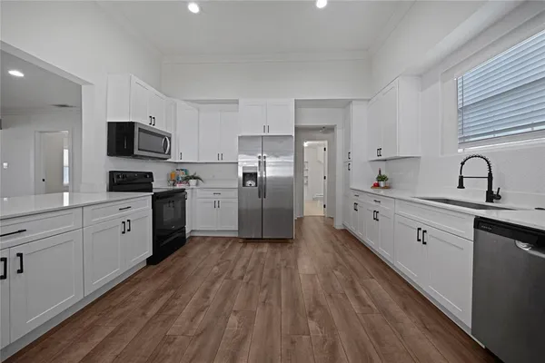 a kitchen with stainless steel appliances granite countertop a refrigerator a stove top oven a sink dishwasher and a refrigerator with wooden floor