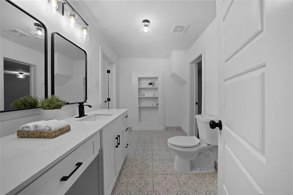 a bathroom with a granite countertop sink a toilet and a large mirror