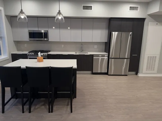 a kitchen with a sink a microwave a refrigerator and chairs