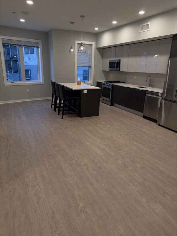 14 Ward Street, Unit 102 Somerville, MA 02143 - Photo 13 of 26 a open kitchen with kitchen island a sink stove and a refrigerator