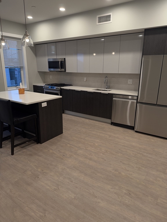 14 Ward Street, Unit 102 Somerville, MA 02143 - Photo 6 of 26 a large kitchen with stainless steel appliances a sink a stove and a refrigerator