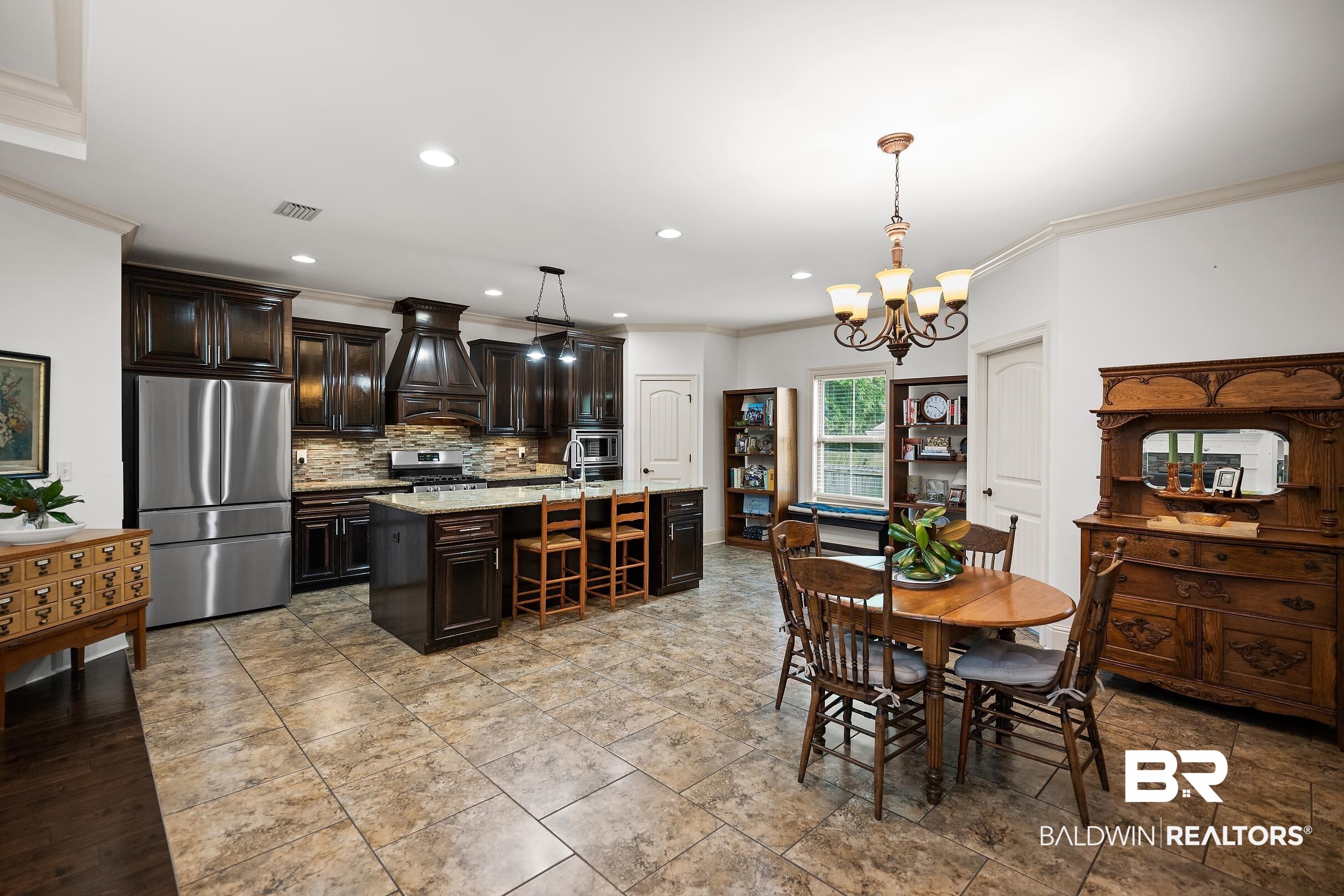 313 Pecan Ridge Boulevard Fairhope, AL 36532 - Photo 9 of 51 Expansive kitchen and dining area featuring dark wood cabinetry, stainless steel appliances, a center island with seating, a tile backsplash, and recessed lighting