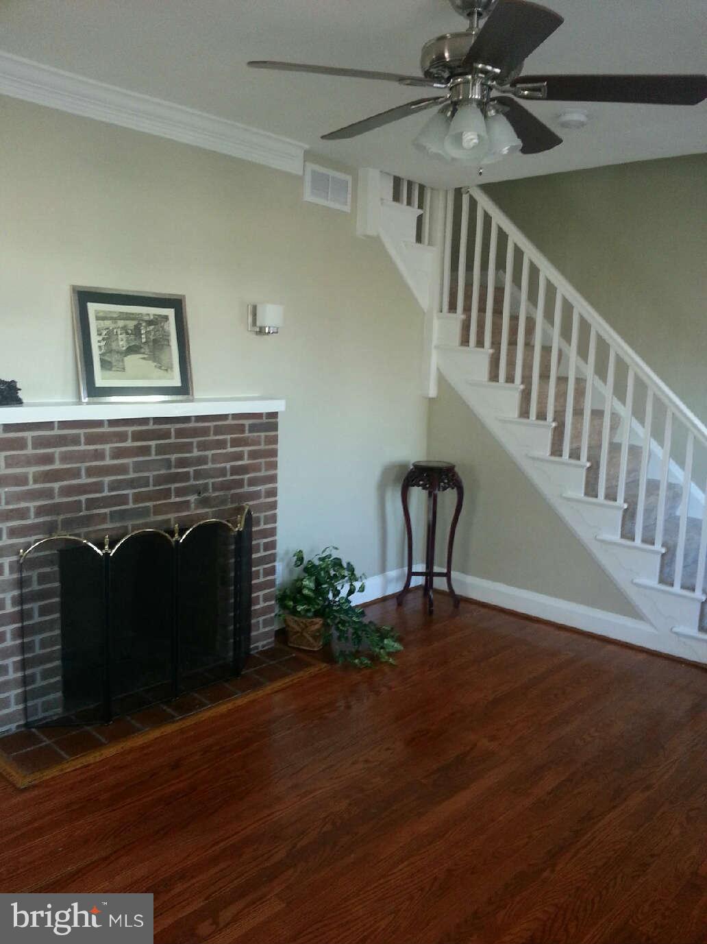 414 North Bend Road Baltimore, MD 21229 - Photo 19 of 27 a view of a livingroom with a fireplace a ceiling fan and wooden floor