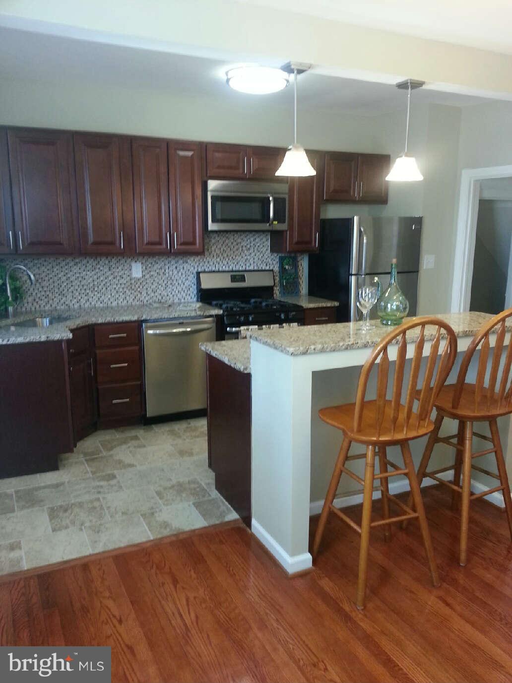 414 North Bend Road Baltimore, MD 21229 - Photo 3 of 27 a kitchen with granite countertop wooden floors and wooden cabinets