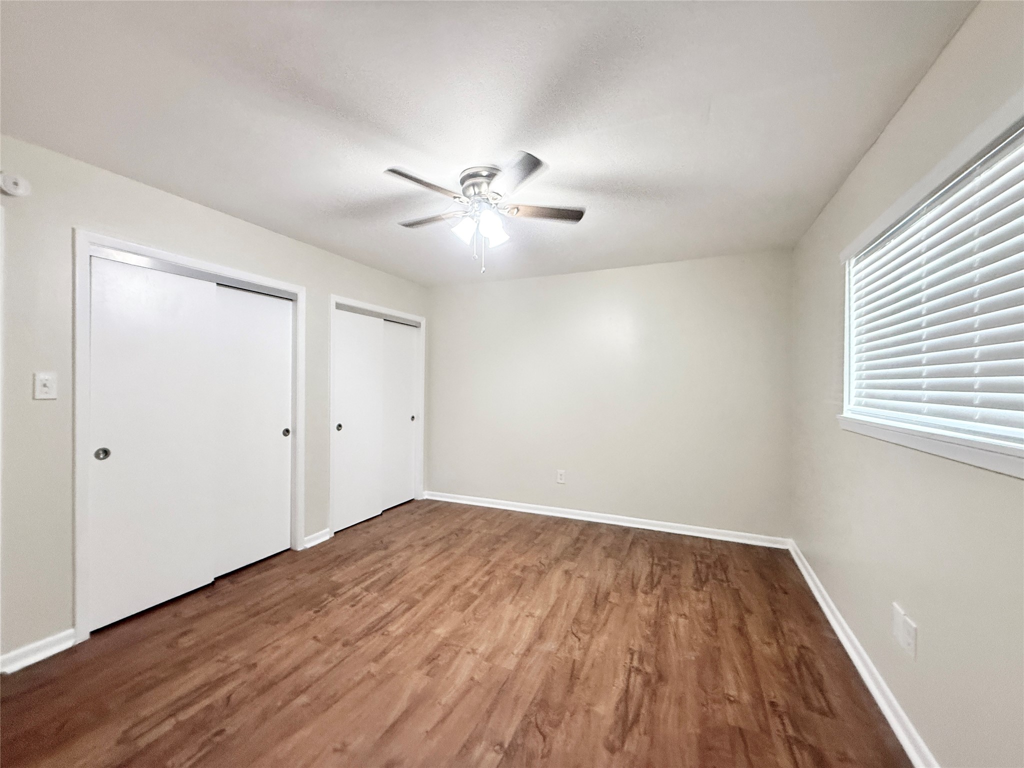 321 East Cedar Street, Unit 7 Angleton, TX 77515 - Photo 11 of 16 wooden floor in an empty room with a window