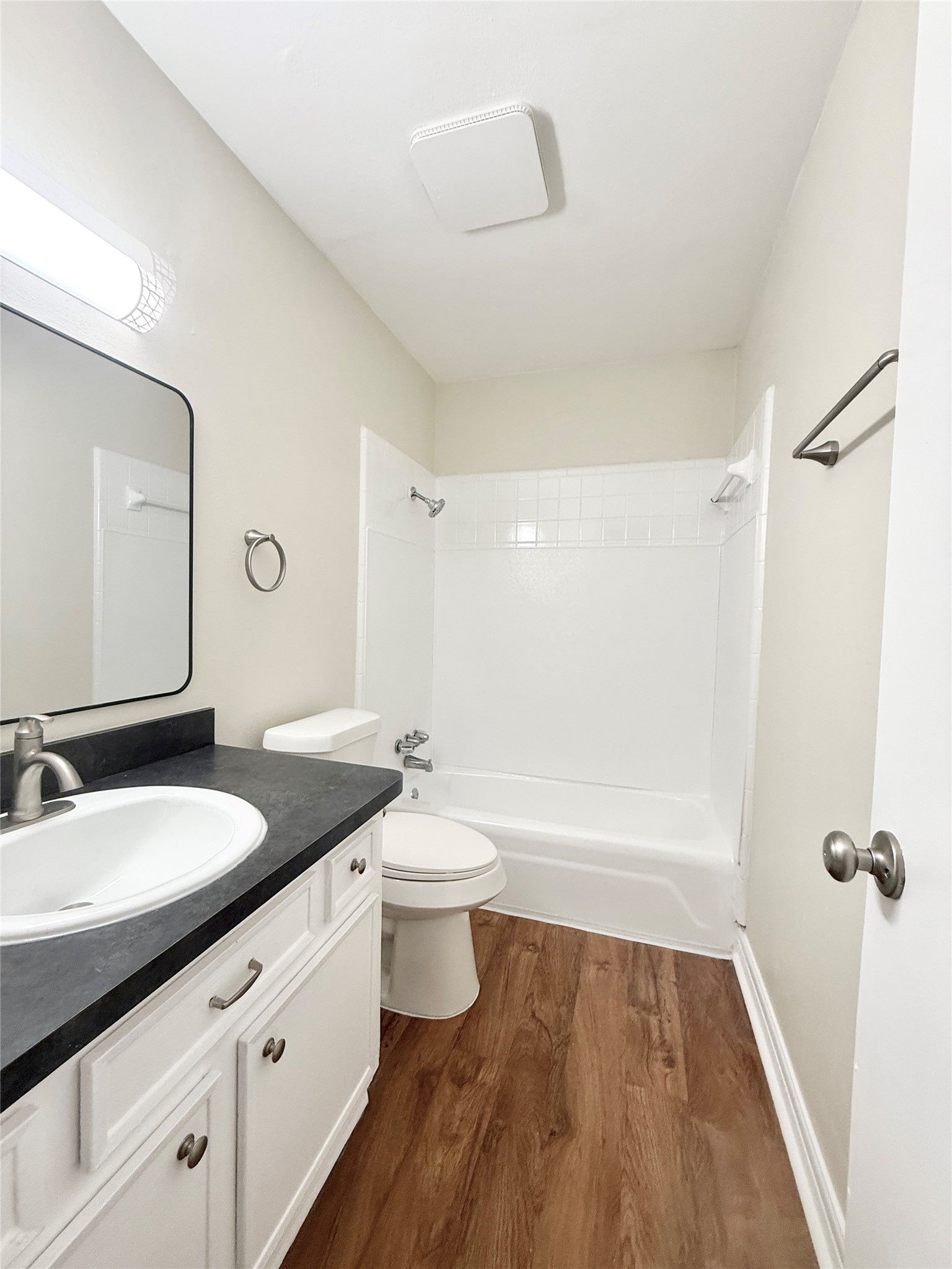 321 East Cedar Street, Unit 7 Angleton, TX 77515 - Photo 13 of 16 a bathroom with a granite countertop sink toilet a large mirror a shower and bathtub