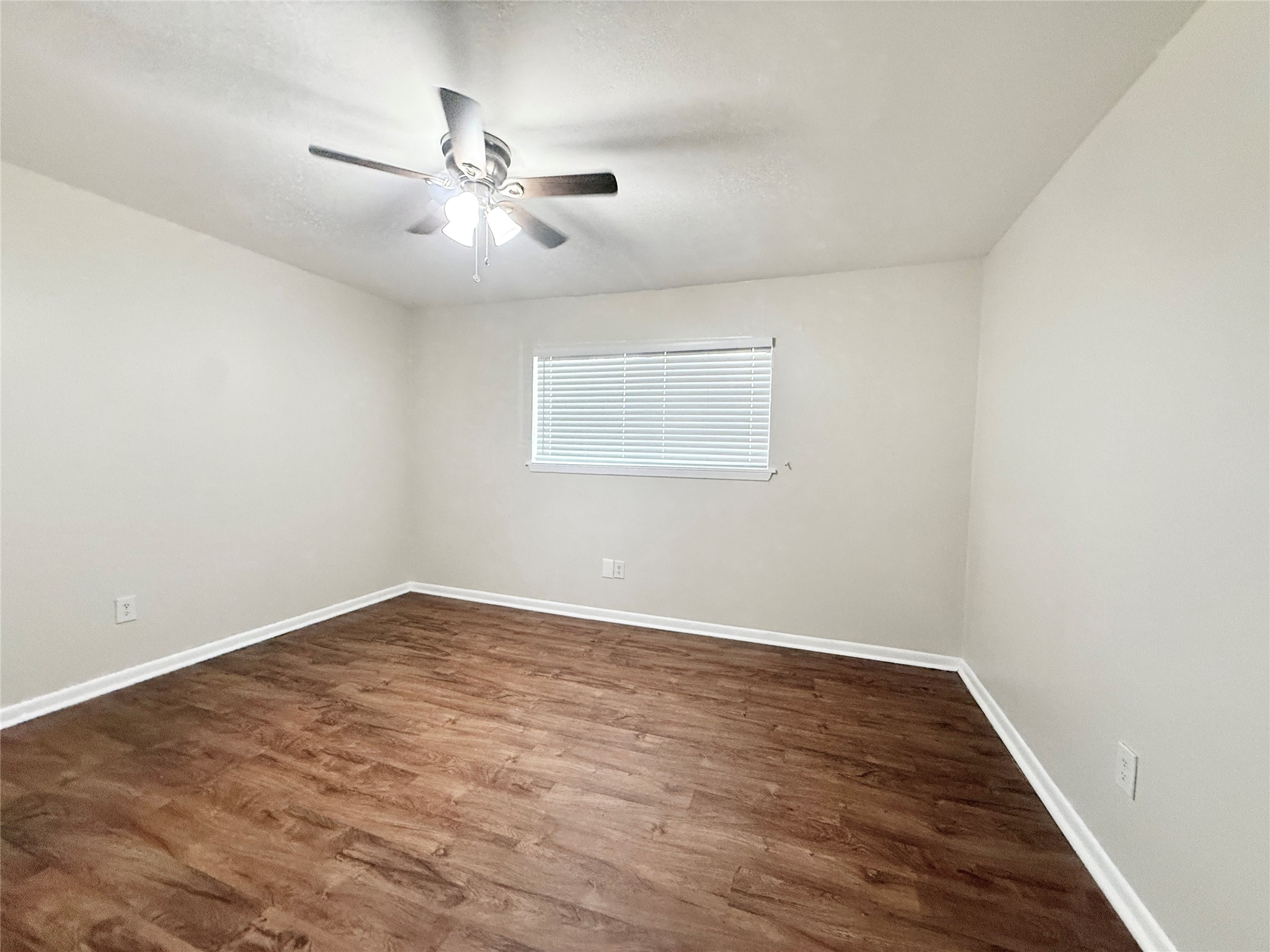 321 East Cedar Street, Unit 7 Angleton, TX 77515 - Photo 9 of 16 an empty room with wooden floor fan and windows
