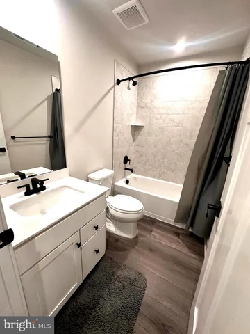 a bathroom with a bathtub shower sink vanity mirror and toilet