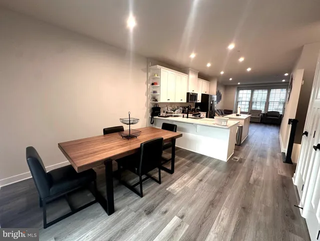 a kitchen with a table chairs a sink dishwasher stove and cabinets with wooden floor