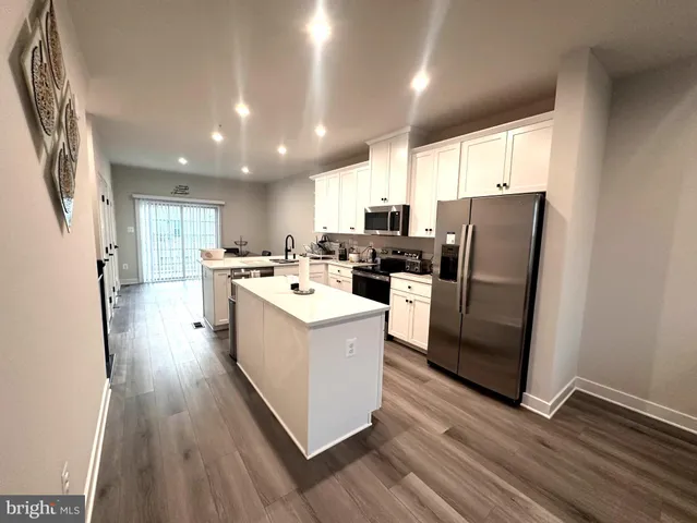 a kitchen with stainless steel appliances a refrigerator a sink dishwasher and a stove with wooden floor