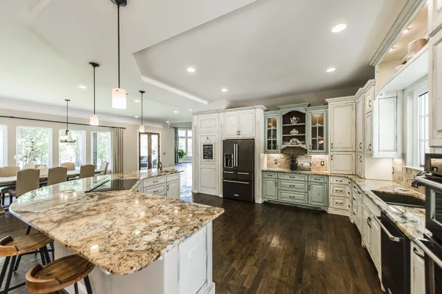 a kitchen with stainless steel appliances kitchen island granite countertop a stove refrigerator and cabinets