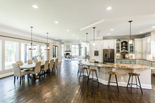 a view of a dining room and livingroom with furniture wooden floor kitchen chandelier