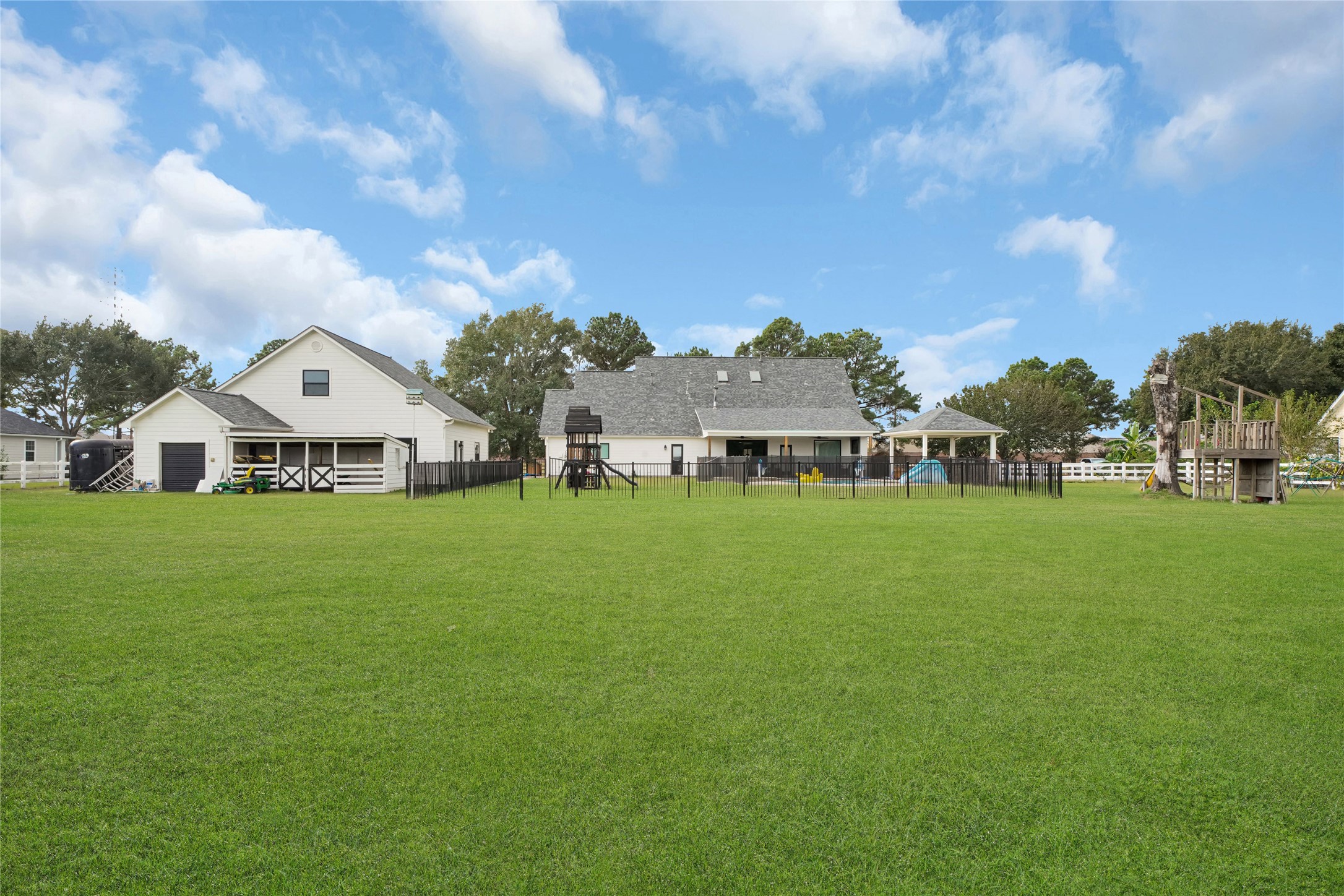 4730 Pitts Road Katy, TX 77493 - Photo 26 of 36 Spacious backyard with lush green lawn, featuring a playground area and an in-ground pool, complemented by a cozy house with an attached garage.
