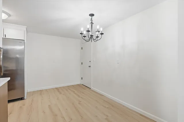 a view of a hallway with wooden floor and a chandelier
