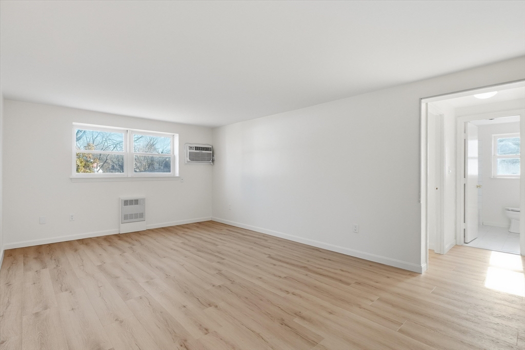 237 Main Street, Unit A4 Reading, MA 01867 - Photo 8 of 22 an empty room with wooden floor and windows