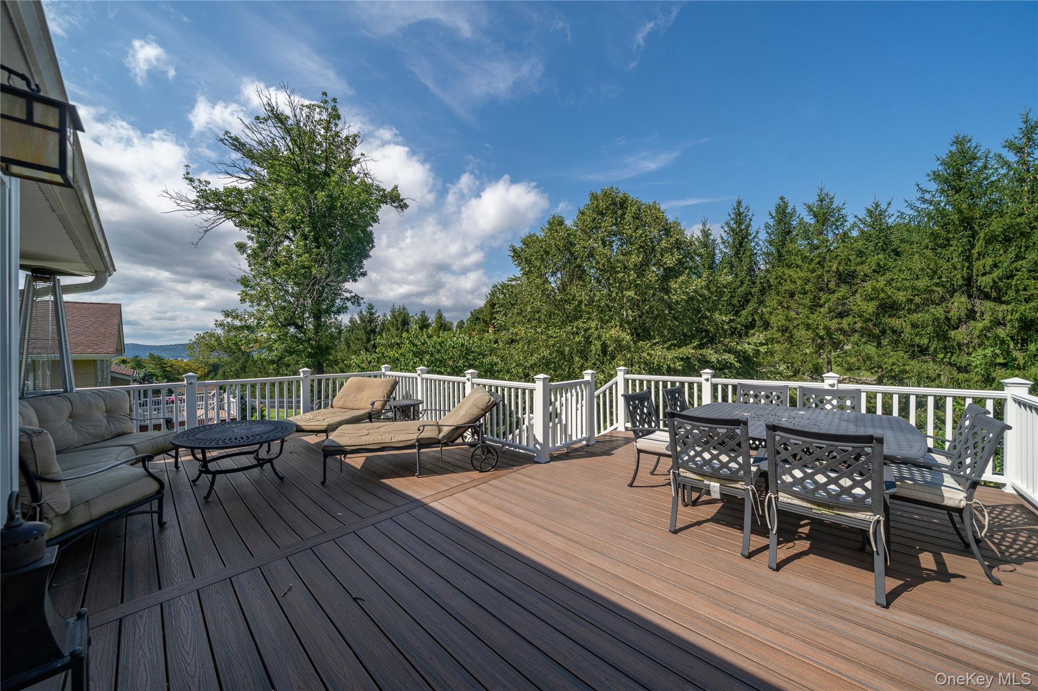 53 Tarryhill Road Tarrytown, NY 10591 - Photo 9 of 35 Step outside to the expansive deck, with generous space for outdoor dining and lounging while enjoying the surrounding scenery and seasonal views of the Hudson River.
