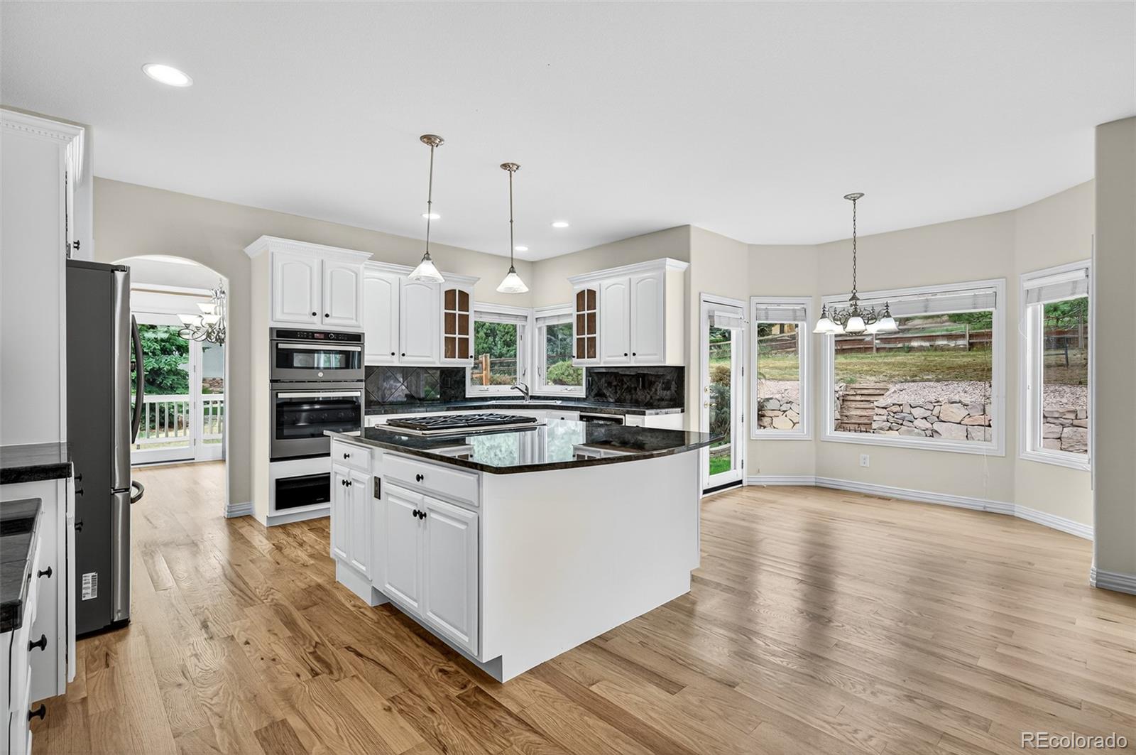 8389 Owl Roost Court Parker, CO 80134 - Photo 26 of 50 a kitchen with stainless steel appliances granite countertop a stove a refrigerator and a wooden floors
