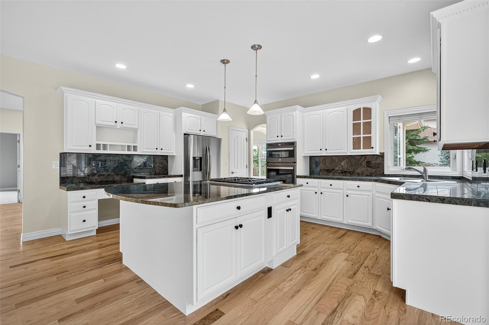 8389 Owl Roost Court Parker, CO 80134 - Photo 27 of 50 a large kitchen with stainless steel appliances and white cabinets