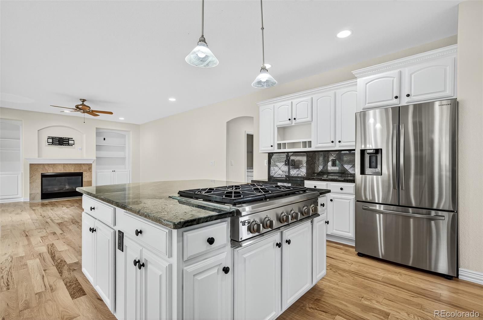 8389 Owl Roost Court Parker, CO 80134 - Photo 28 of 50 a kitchen with stainless steel appliances granite countertop a stove a refrigerator a sink and a oven with wooden floor