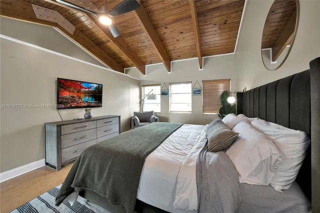 a bedroom with a bed a mirror on the dresser and a flat screen tv