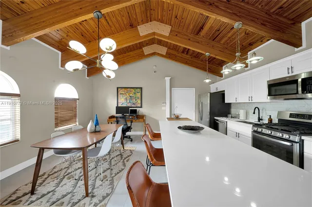 a kitchen with stainless steel appliances a table and chairs in it