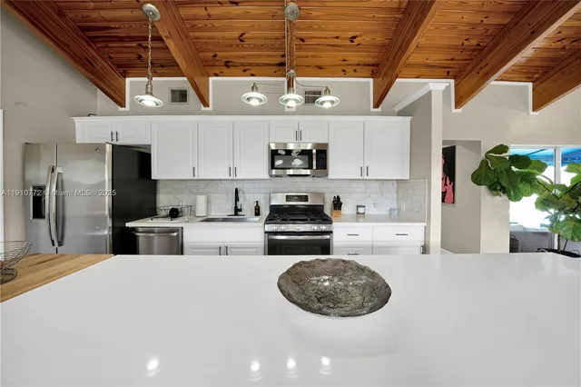 a kitchen with stainless steel appliances granite countertop a refrigerator a sink dishwasher a oven with a dining table and chairs