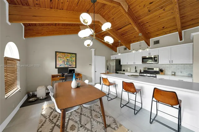 a kitchen with stainless steel appliances granite countertop a stove a sink a dining table and chairs with the cabinets