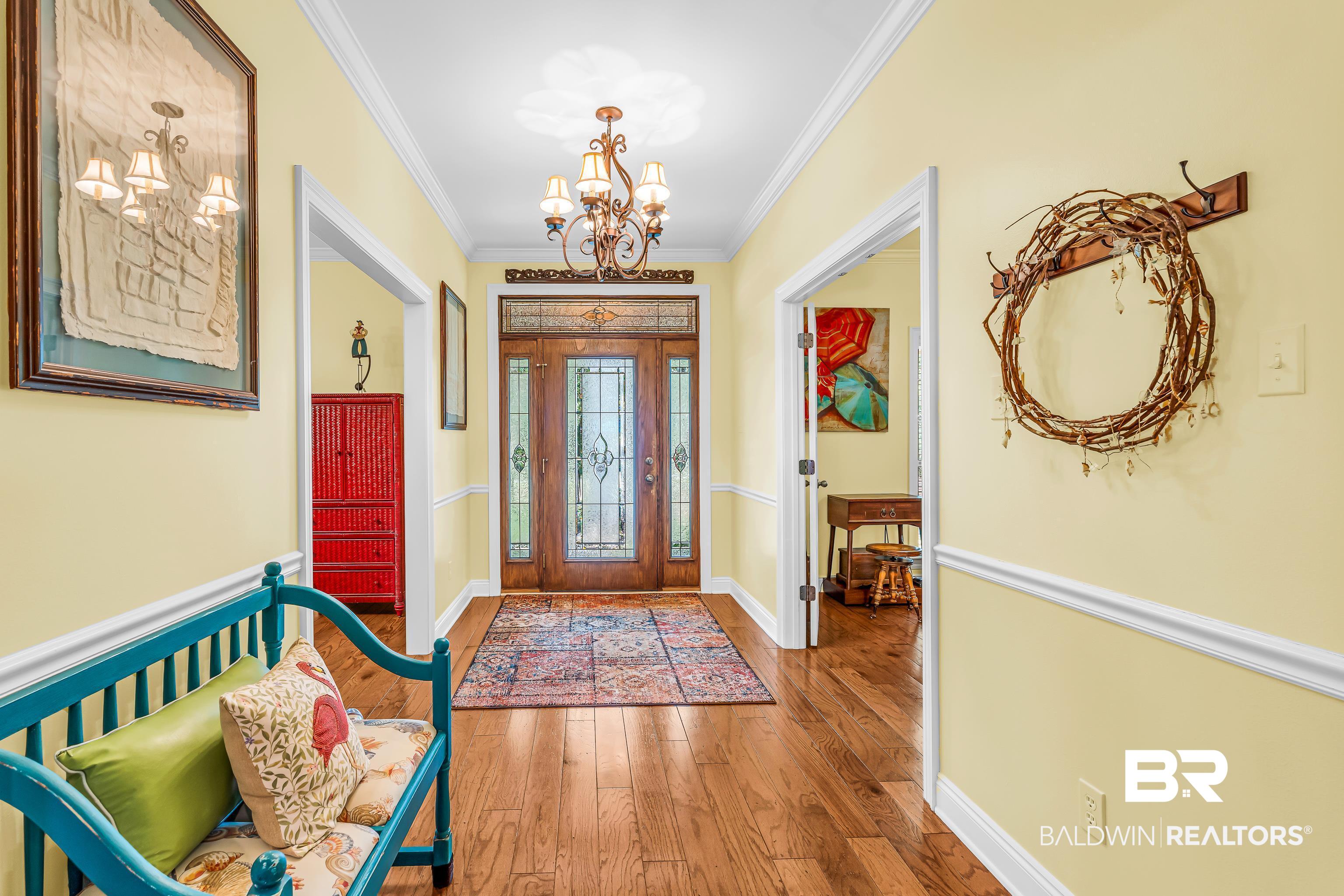 7014 Blakeley Road Daphne, AL 36527 - Photo 20 of 45 Entryway featuring polished wood-finish flooring, a decorative chandelier, and a wood-paneled door with frosted glass inserts and transom